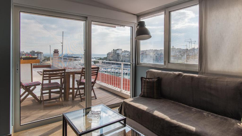 ein Wohnzimmer mit einem Sofa und einem Tisch auf dem Balkon in der Unterkunft Piraeus Apartment with Endless View in Piräus