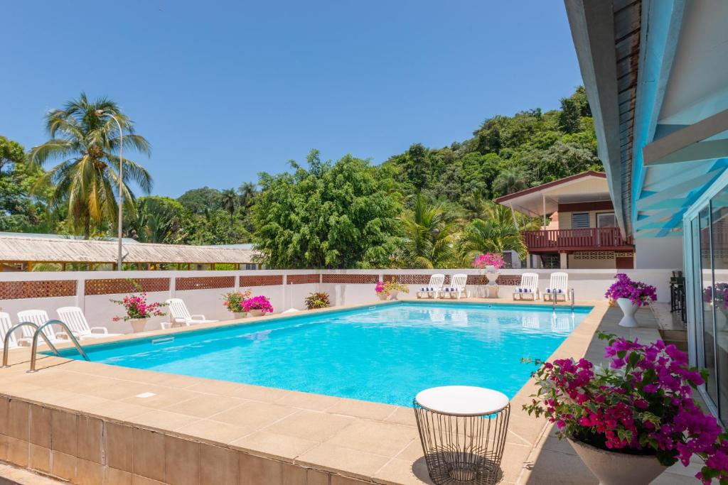 a swimming pool in a resort with chairs and flowers at The Originals City, Hôtel Belova, Cayenne Sud (Inter-Hotel) in Montjoly