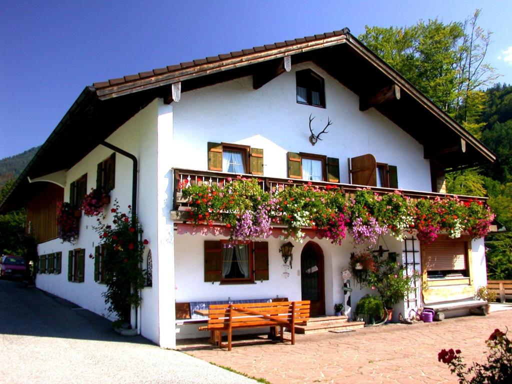 ein weißes Haus mit einer Bank davor in der Unterkunft Haus Wiesenrand in Berchtesgaden
