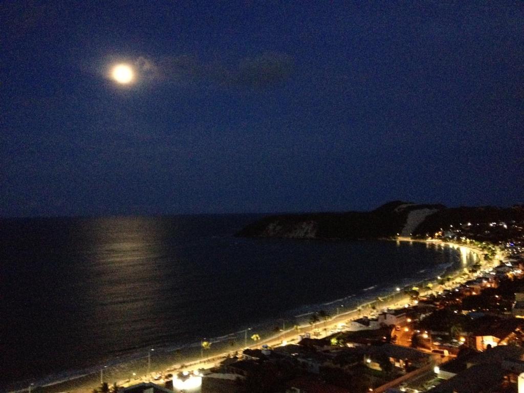 una vista de la playa por la noche con luna llena en Bela vista de Ponta Negra, en Natal