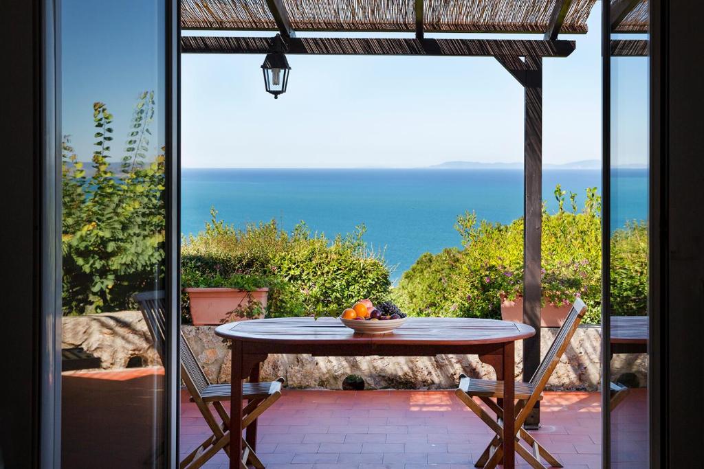 uma mesa e cadeiras num pátio com vista para o oceano em Residenza Turistico Alberghiera Le Poste del Pianone em Santa Liberata