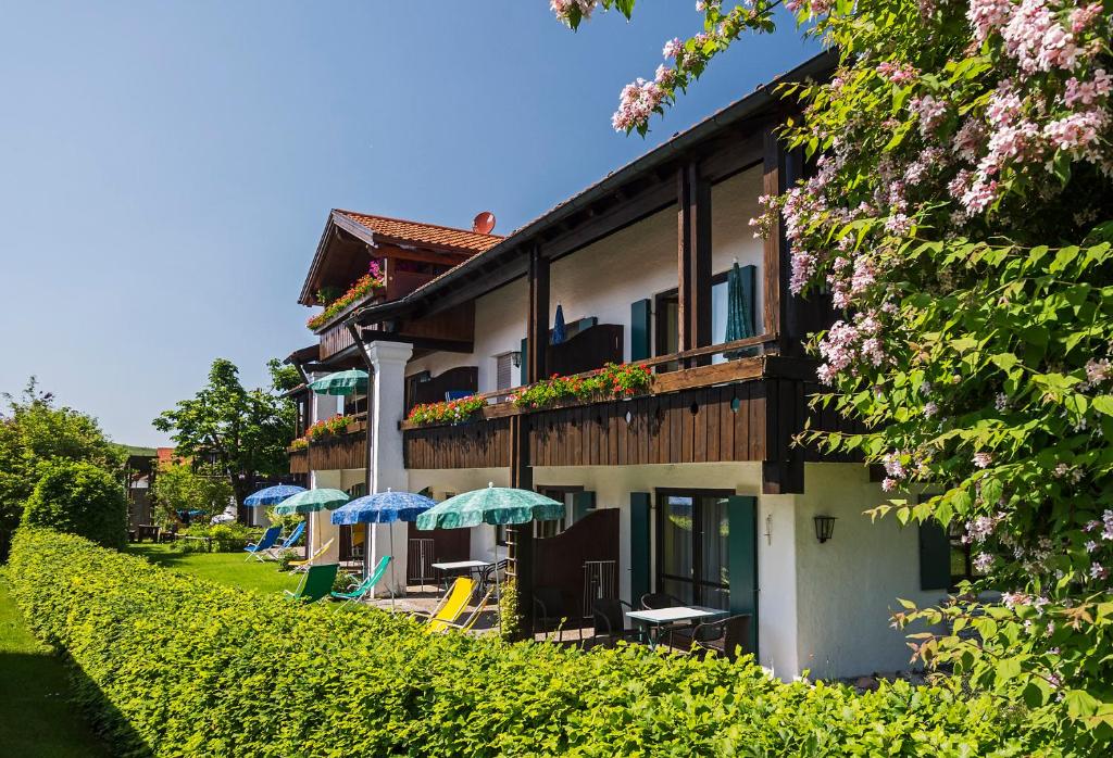 un edificio con sombrillas y sillas delante de él en Allgäu Ferienhaus Strobel en Roßhaupten