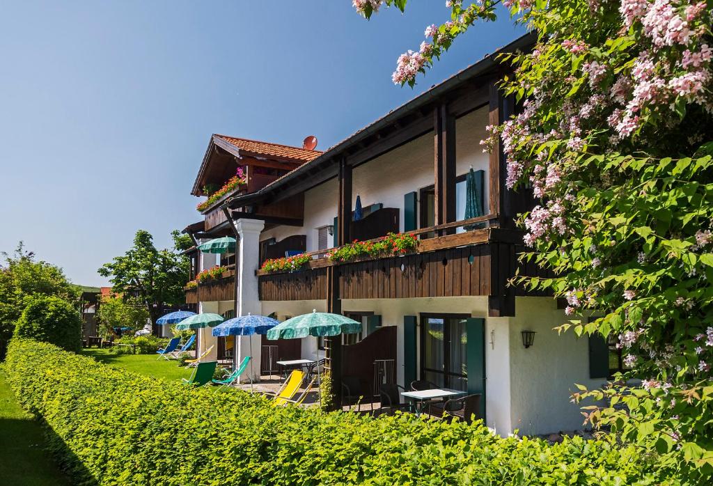 ein Gebäude mit Sonnenschirmen und Stühlen davor in der Unterkunft Allgäu Ferienhaus Strobel in Roßhaupten