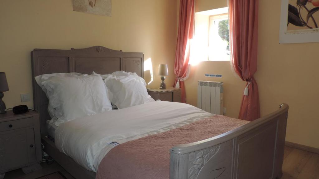 a bedroom with a bed with white sheets and a window at Le Mas de Cascabel in Causse et Diege
