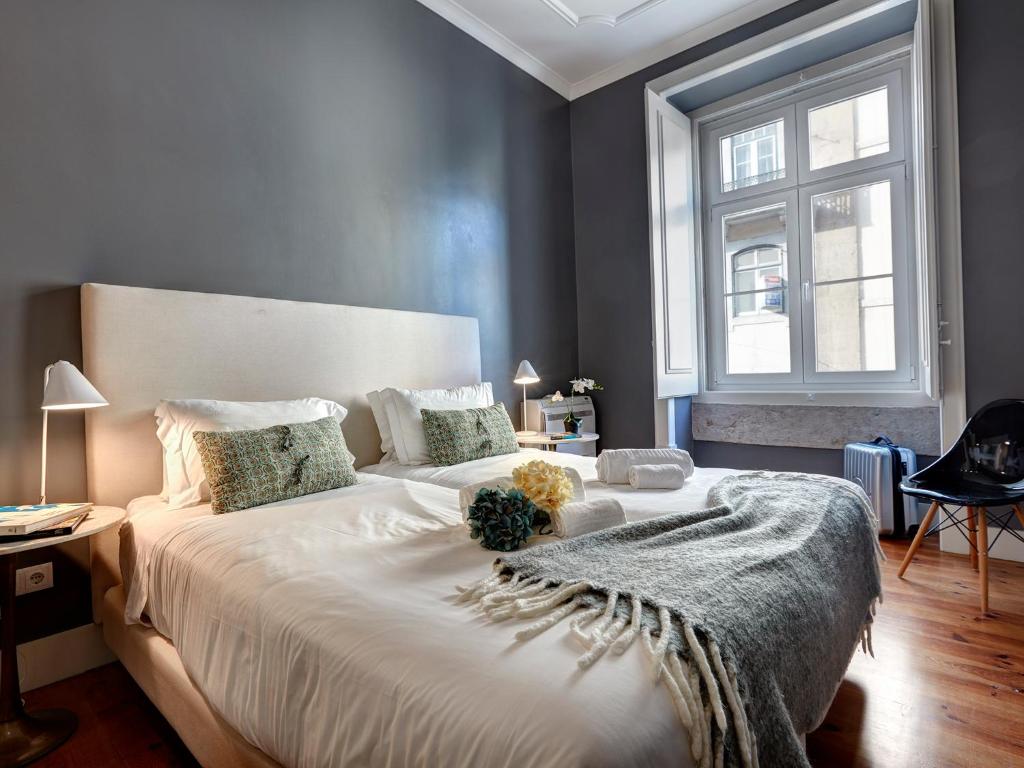 - une chambre avec un grand lit blanc et une fenêtre dans l'établissement Lisbon Canaan Boutique Apartments Fanqueiros 114 by Get Your Stay, à Lisbonne