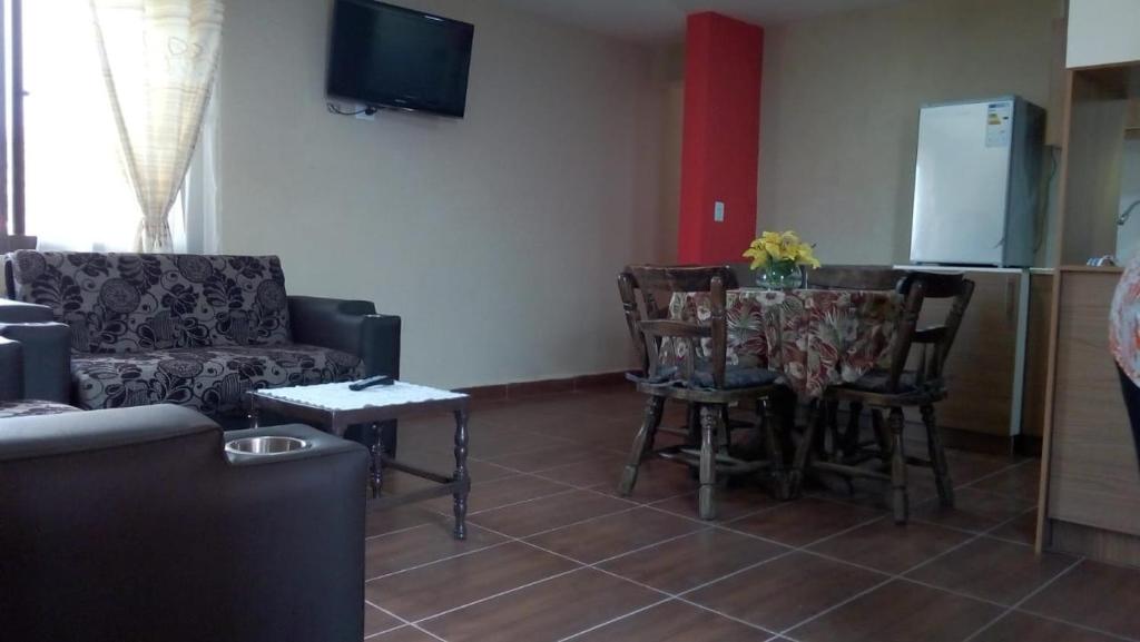 sala de estar con mesa, sillas y nevera en Apartamento Golden Junior, en Cochabamba