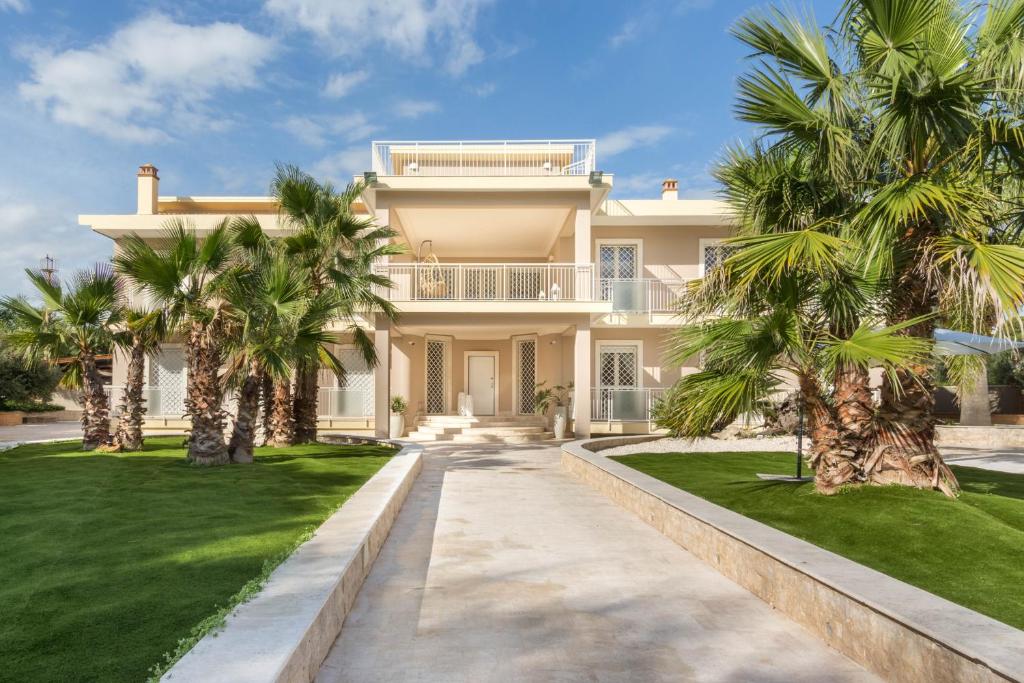 een groot huis met palmbomen ervoor bij Villa Furoa in Quartu SantʼElena