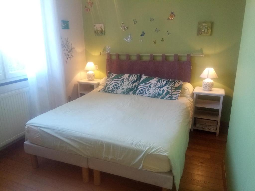 a bedroom with a bed and two night stands with lamps at Chambres d'Hôtes La Ferme du Bout de la Ville in Criquebeuf-en-Caux