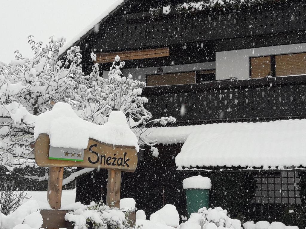 a snow covered sign in front of a building at Snežak (Snowman) in Bohinj