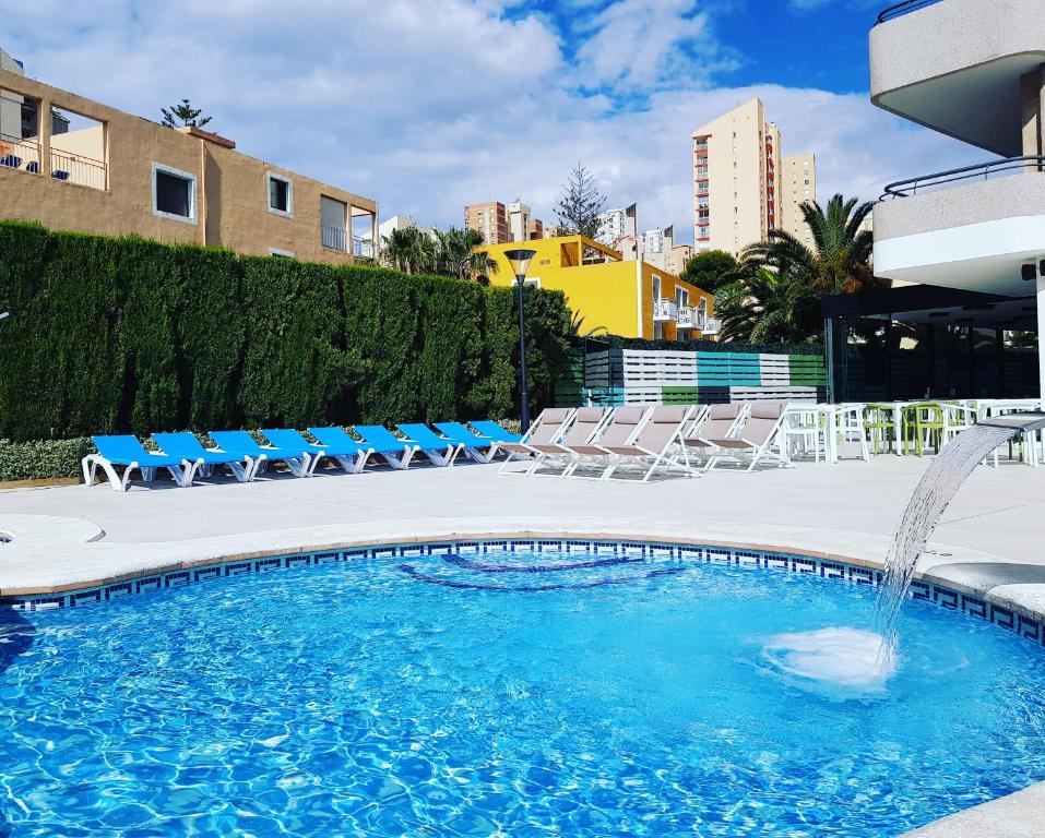 a swimming pool with chairs and a fountain at Primavera Loix in Benidorm