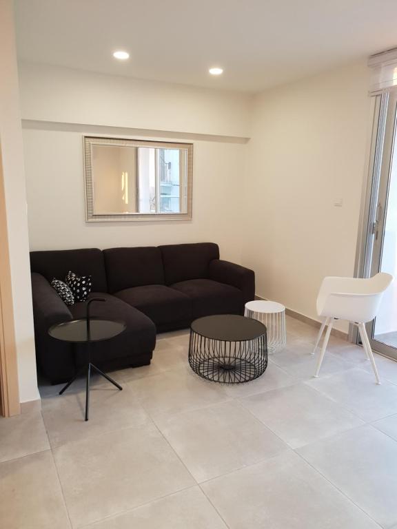 ein Wohnzimmer mit einem schwarzen Sofa und 2 Tischen in der Unterkunft Egkomi Luxury Suites in Nikosia