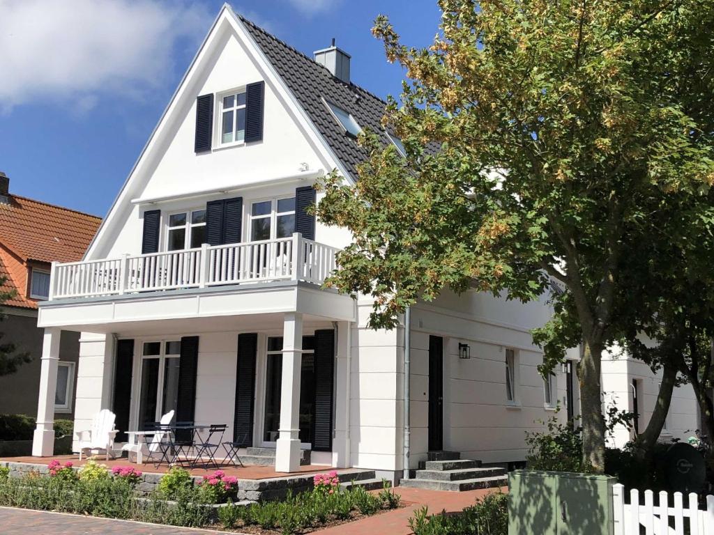 Dieses weiße Haus verfügt über eine Veranda und einen Balkon. in der Unterkunft Kleine Charlotte - Traumwohnung mit Terrasse für 4 Personen in Wangerooge