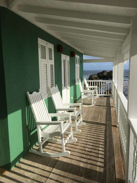 a row of chairs sitting on a porch overlooking the ocean at The Atlantis Historic Inn in Saint Joseph