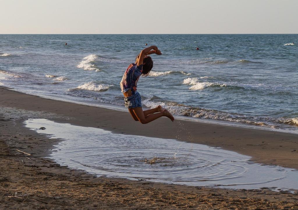 a young girl jumping into the water on the beach at Casa Dellestate in Grottammare