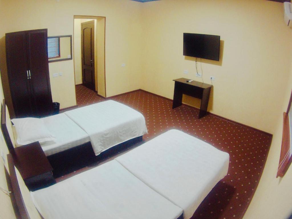 a hotel room with two beds and a flat screen tv at Bek Shahrisabz in Shahrisabz