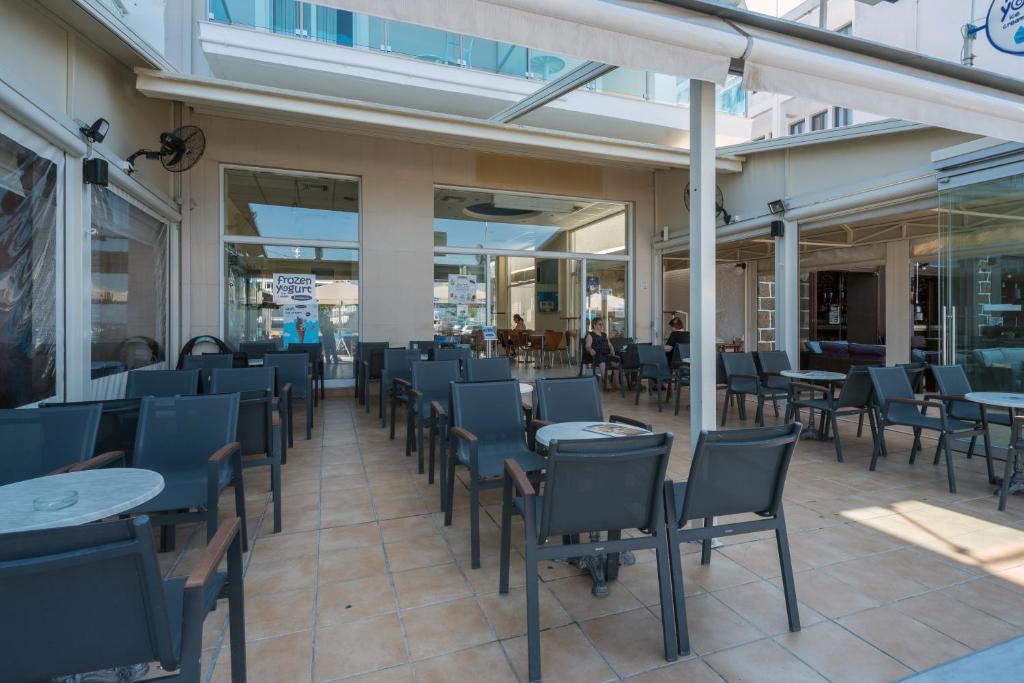 a restaurant with tables and chairs on a patio at Hotel Plaza in Nea Stira