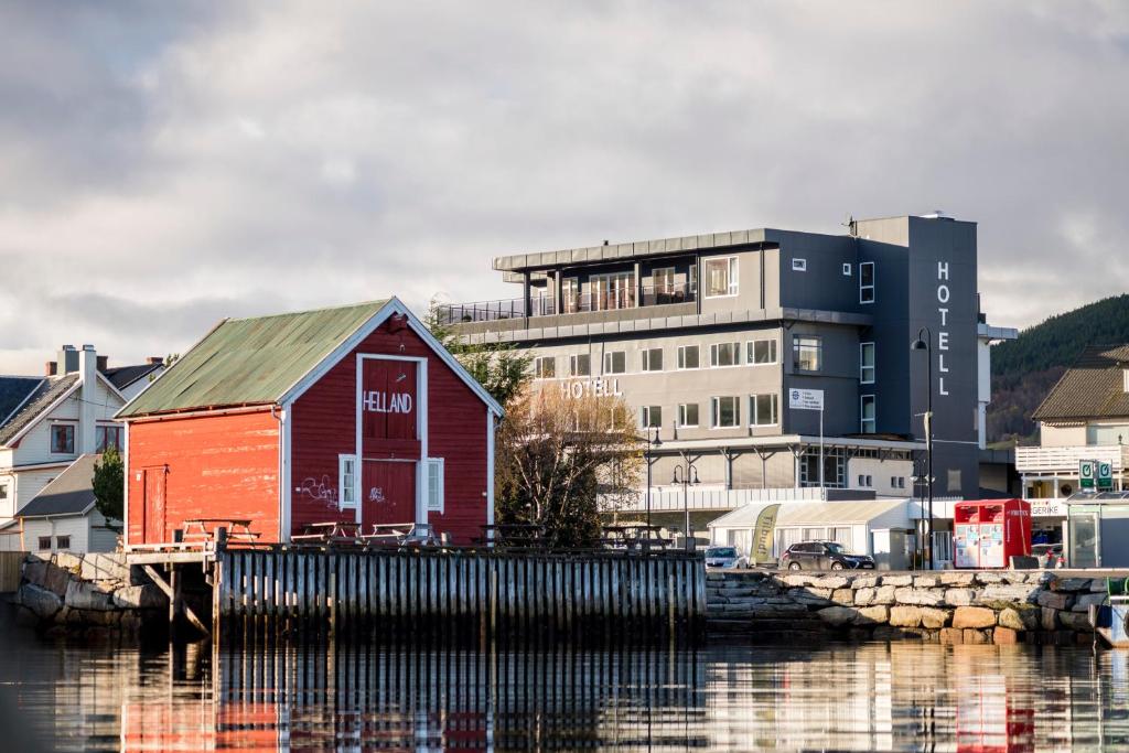 a red building sitting on the water in front of a building at Vestnes Fjordhotell in Vestnes