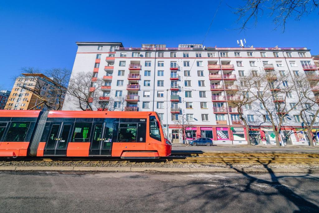 an orange train on the tracks in front of a building at MODRÝ APARTMÁN, Račianska 29, BRATISLAVA in Bratislava