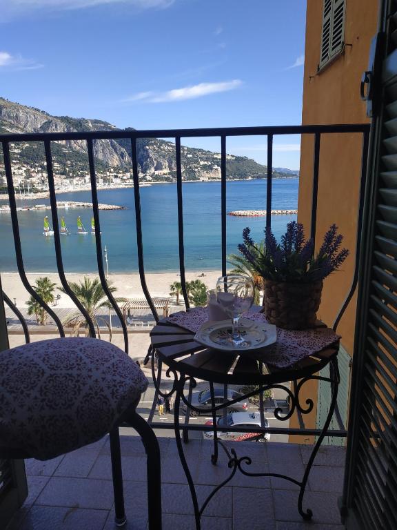 a table and chairs on a balcony with a view of the beach at Vista mare vecchia città in Menton