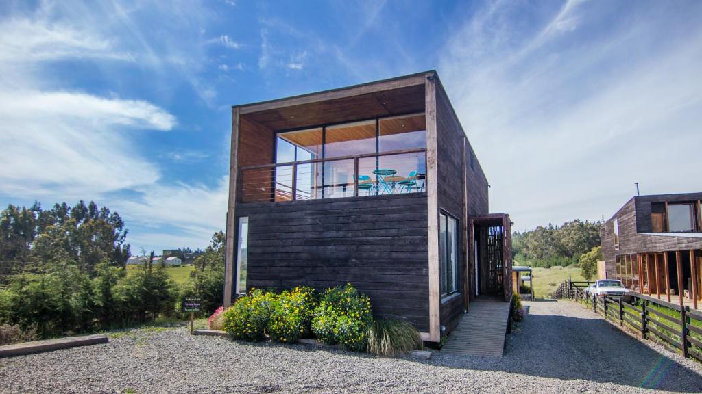 a small wooden house with a large window at Lodge KARKÚ in Pichilemu