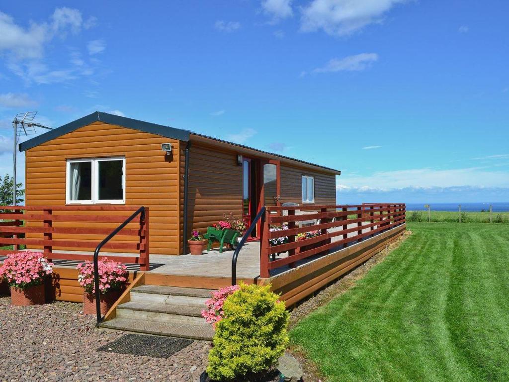 eine kleine Hütte mit einem Holzzaun und einer Veranda in der Unterkunft Golden Oak Chalet in Dunbar