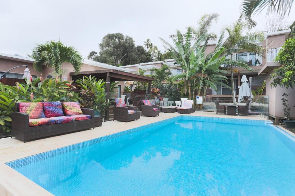 a pool with chairs and a couch next to a house at Kia Orana Villas and Spa in Rarotonga