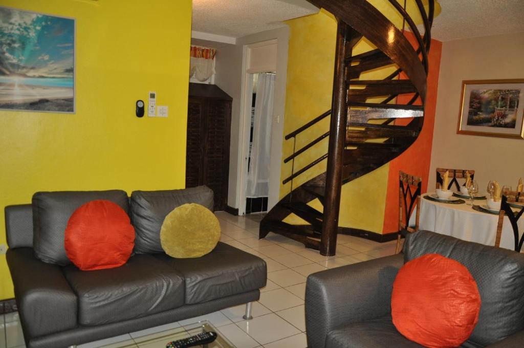 un soggiorno con divano e cuscini arancioni e gialli. di Beach PentHouse A25 Sandcastles a Ocho Rios