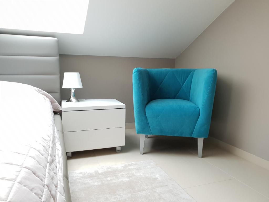 una silla azul en un dormitorio junto a una cama en Wellness Apartmány EMPORIO, en Loštice