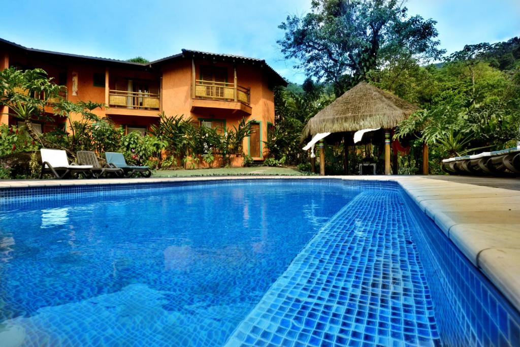 a swimming pool in front of a house at Pousada Forte Rocha in Ilhabela