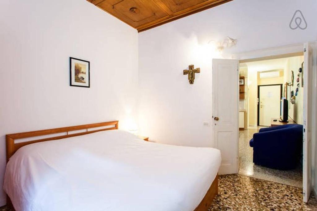 a bedroom with a white bed and a cross on the wall at Melusina Apartments Rialto in Venice