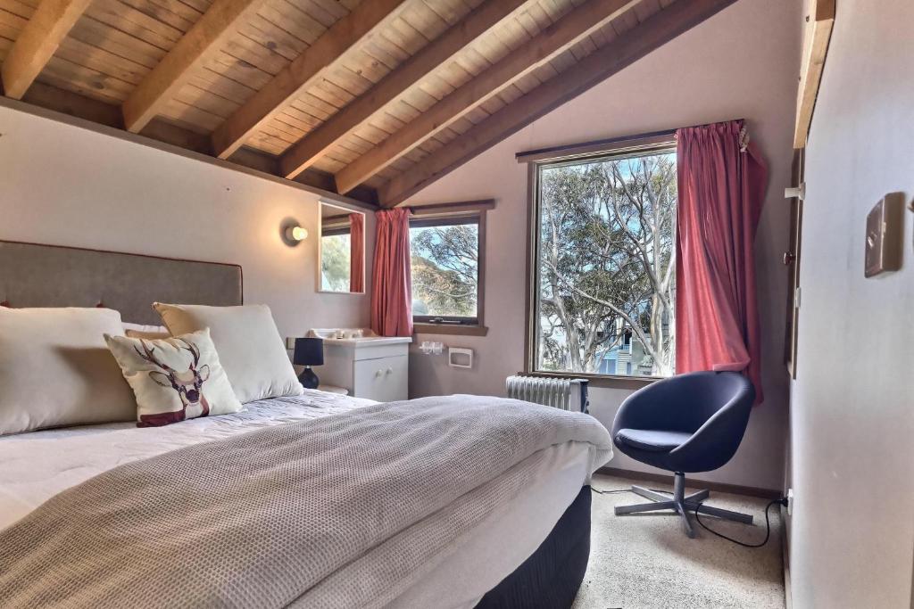 1 dormitorio con 1 cama, 1 silla y 1 ventana en Bindi - Alpine Getaways's Chalet at Tower Rd en Dinner Plain