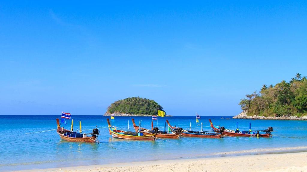 a group of boats sitting in the water on a beach at Tranquil Ocean View Apartment in Kata Beach