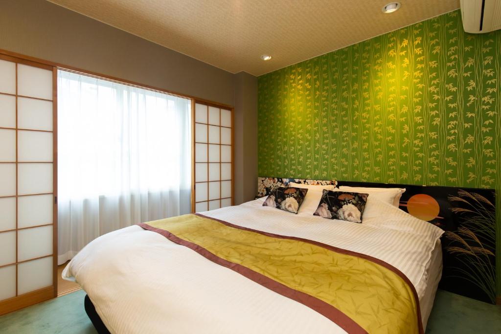 a bedroom with a large bed with a green wall at Matsui Building in Tokyo