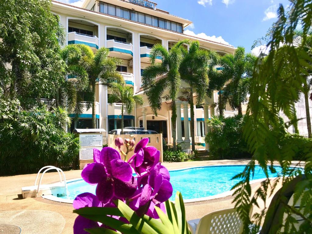 un complexe avec des fleurs violettes en face d'une piscine dans l'établissement Krabi Golden Hill Hotel, à Krabi