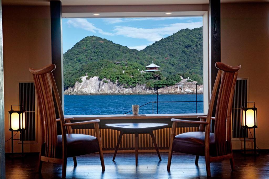 a table and chairs with a view of the ocean at Migiwatei Ochi Kochi in Fukuyama