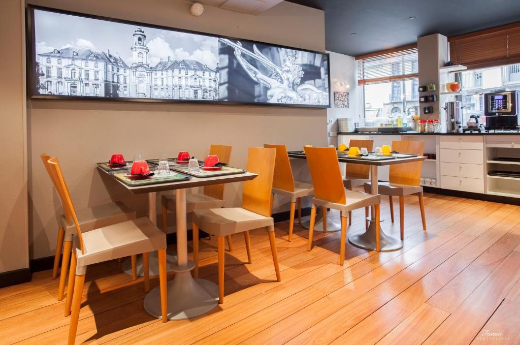 a kitchen with two tables and chairs and a large screen at Hotel Des Lices in Rennes