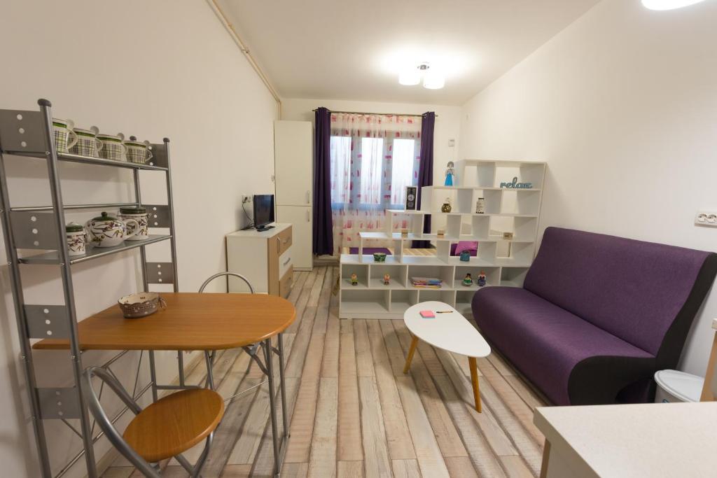 a living room with a purple couch and a table at Garsoniere Central in Satu Mare