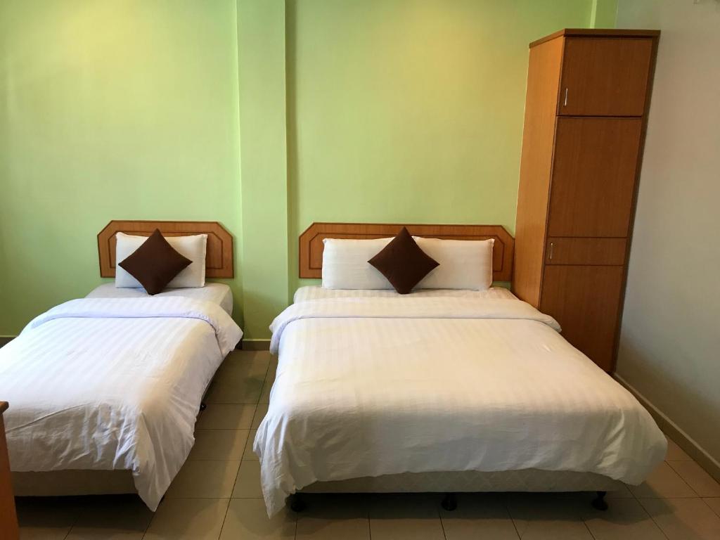 dos camas sentadas una al lado de la otra en una habitación en Kangsar Hotel, en Kuala Kangsar