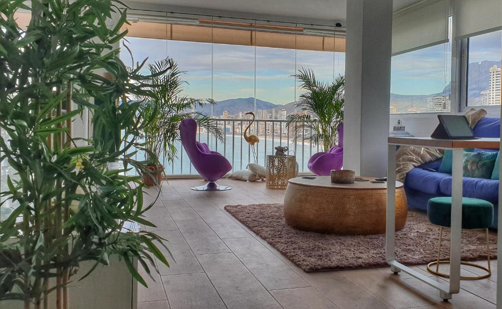 a living room with potted plants and a large window at Portofino Playa in Benidorm