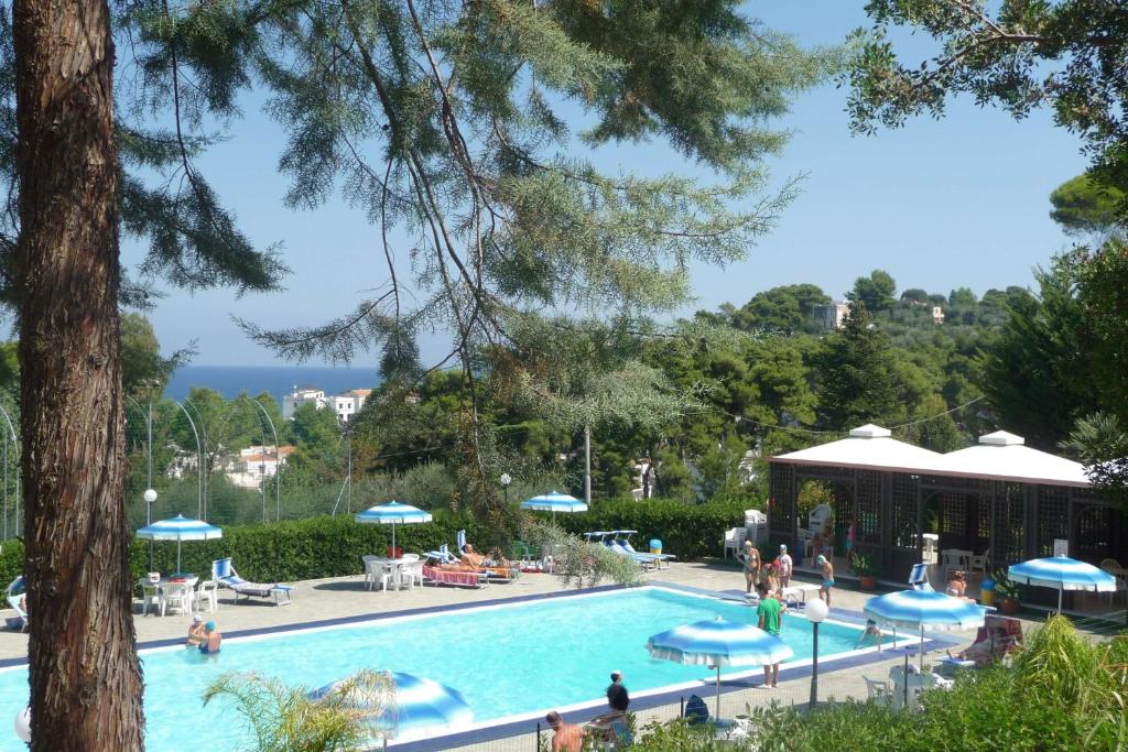 una piscina in un resort con persone sedute intorno di Happy Camp mobile homes in Camping Villaggio Internazionale a San Menaio