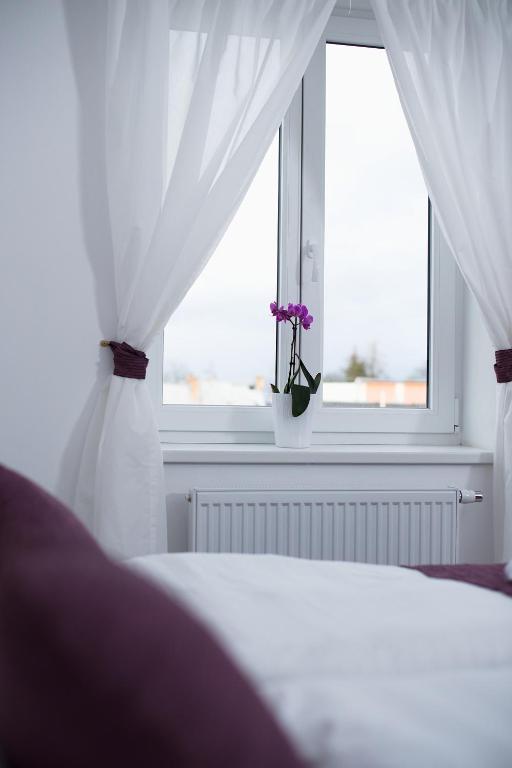 łóżko z białymi zasłonami i oknem z fioletowymi kwiatami w obiekcie Hotel Slavia w mieście Svitavy