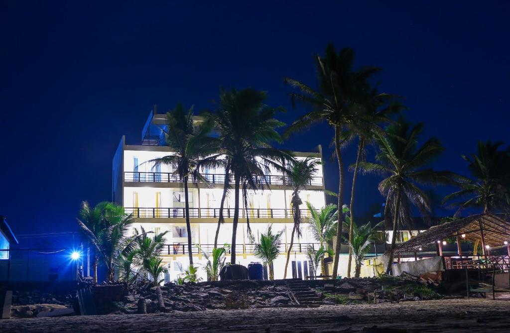 a building on the beach with palm trees at night at OCEAN EDGE HIKKA in Hikkaduwa