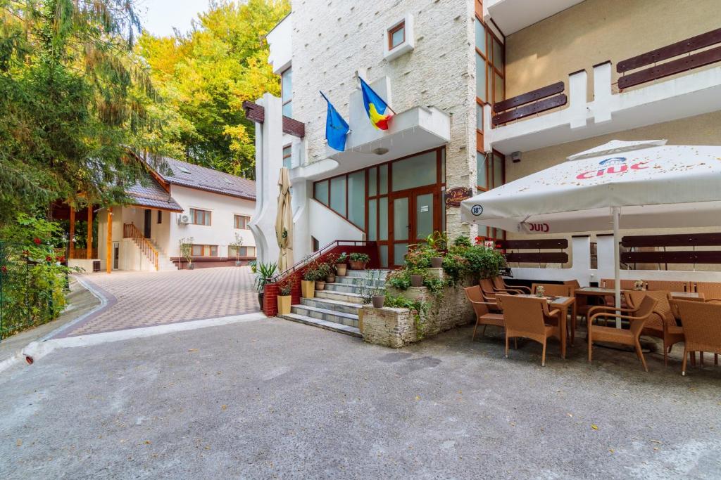 un restaurant avec une table et un parasol devant un bâtiment dans l'établissement Former Ceausescu's Vila Crizantema, à Băile Govora