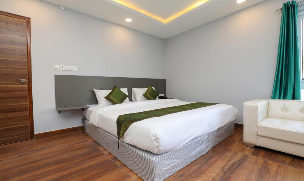 a bedroom with a large bed and a chair at Treebo Trend Apple Villa in Bangalore