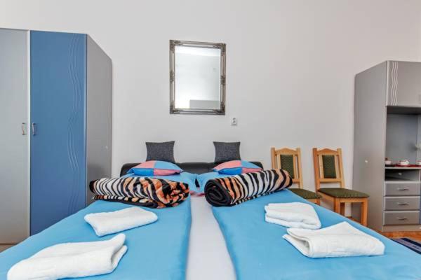 niebieskie łóżko z poduszkami w pokoju w obiekcie Arany Csillag Apartman w Egerze
