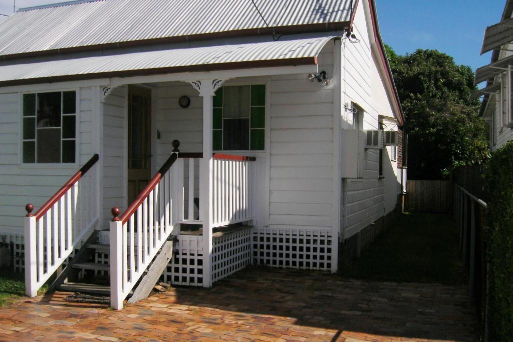 布里斯本的住宿－Pine Cottage，白色的房子,设有门廊和楼梯