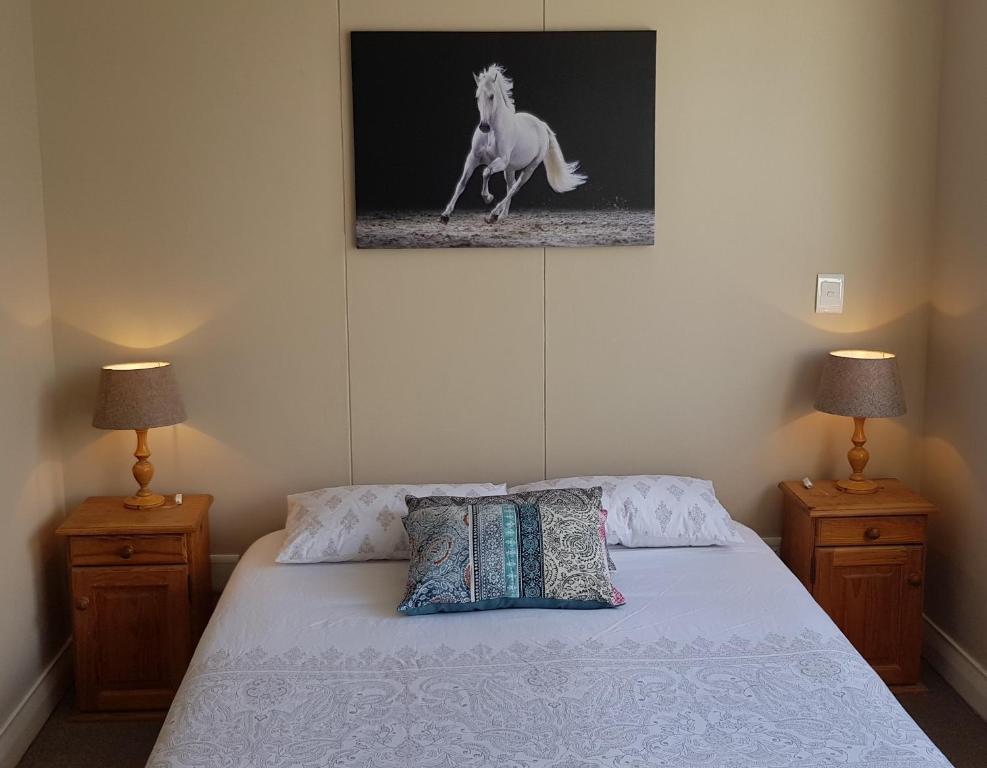 a bedroom with a bed with a picture of a horse at 180 Eden on the Bay, Big Bay in Big Bay