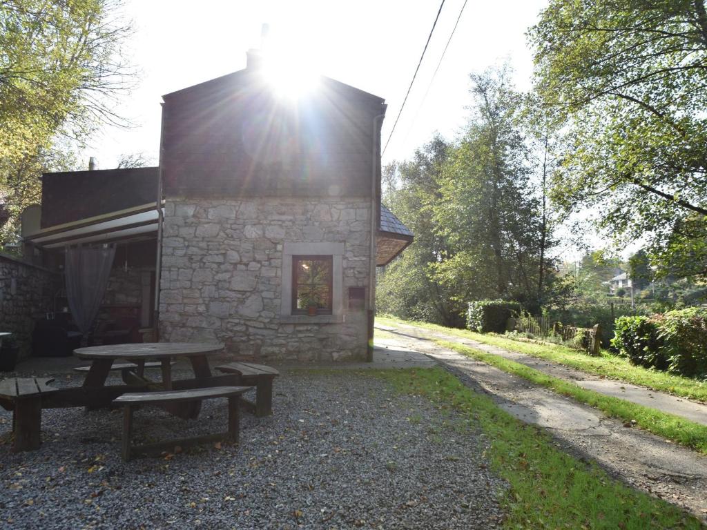una mesa de picnic y un edificio con el sol brillando en Charming gite in Les Avins situated by a stream, en Modave