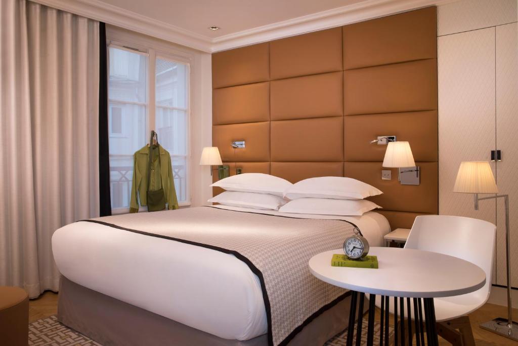 a bedroom with a large white bed and a table at Hôtel R de Paris - Boutique Hotel in Paris