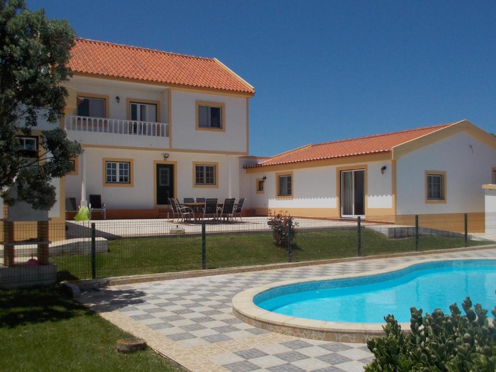 a villa with a swimming pool in front of a house at casa entre praias in Foz do Arelho